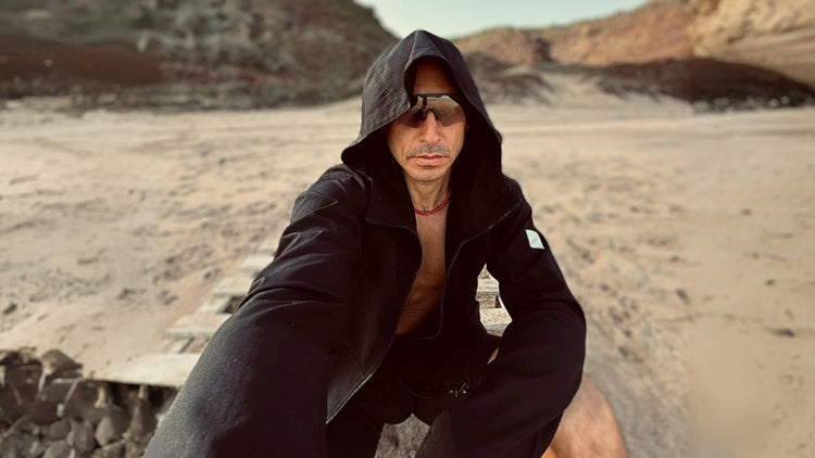 Hafif Dış Giyim Koleksiyonu banner görseli, siyah rüzgarlık mont giymiş adam sahilde oturuyoru ve selfie çekiyor.