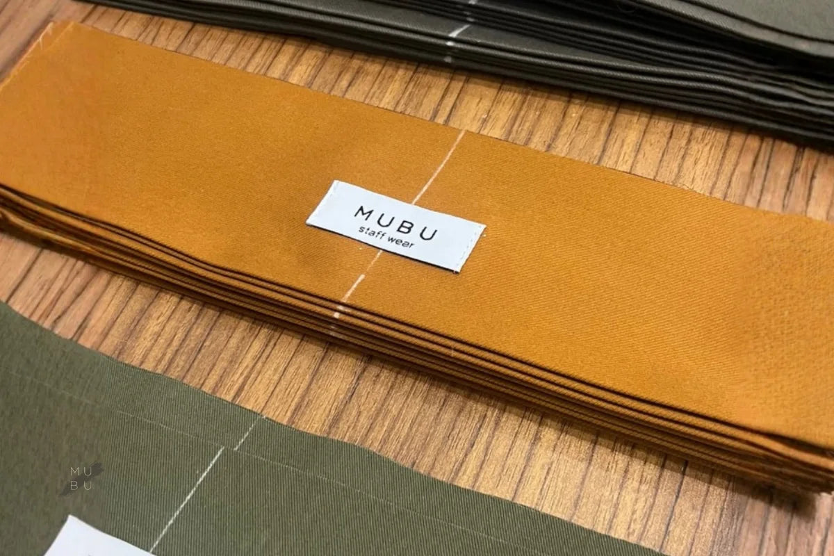 MUBU staff wear ürün etiketi ve kumaş parçası detayı.