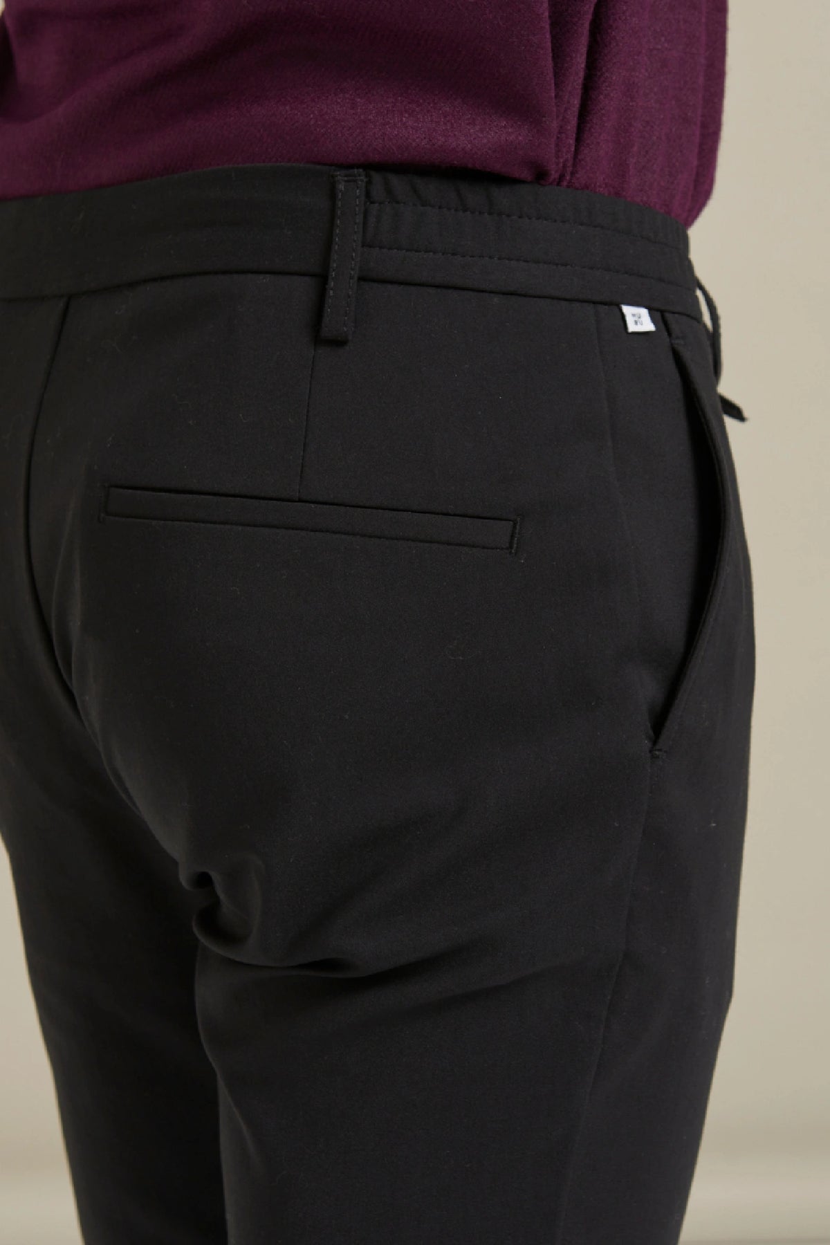 modelin üzerinde duran siyah Gentle Chino pamuklu pantolon arka cep görünümü.