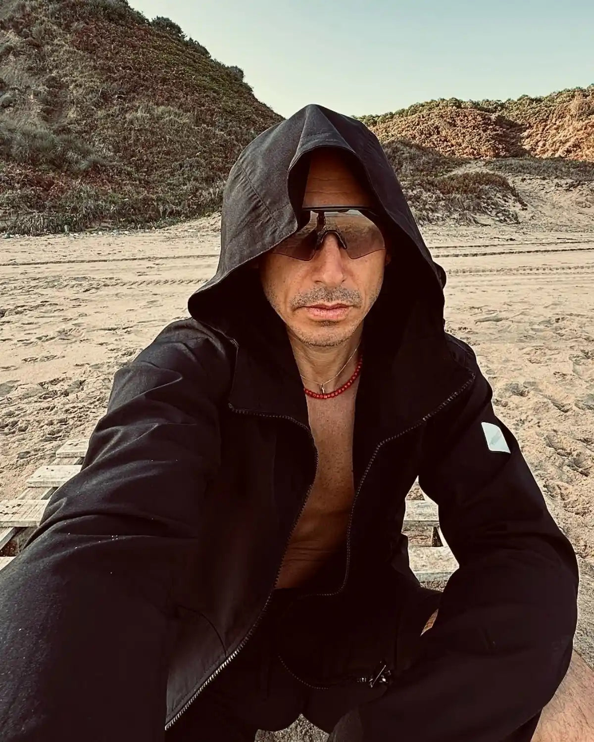 SWAY siyah asimetrik kesim hafif rüzgarlık mont sahilde manken üzerinde selfie çekerken duruşu.